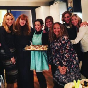 Group of women smiling at the camera with one holding baked goods